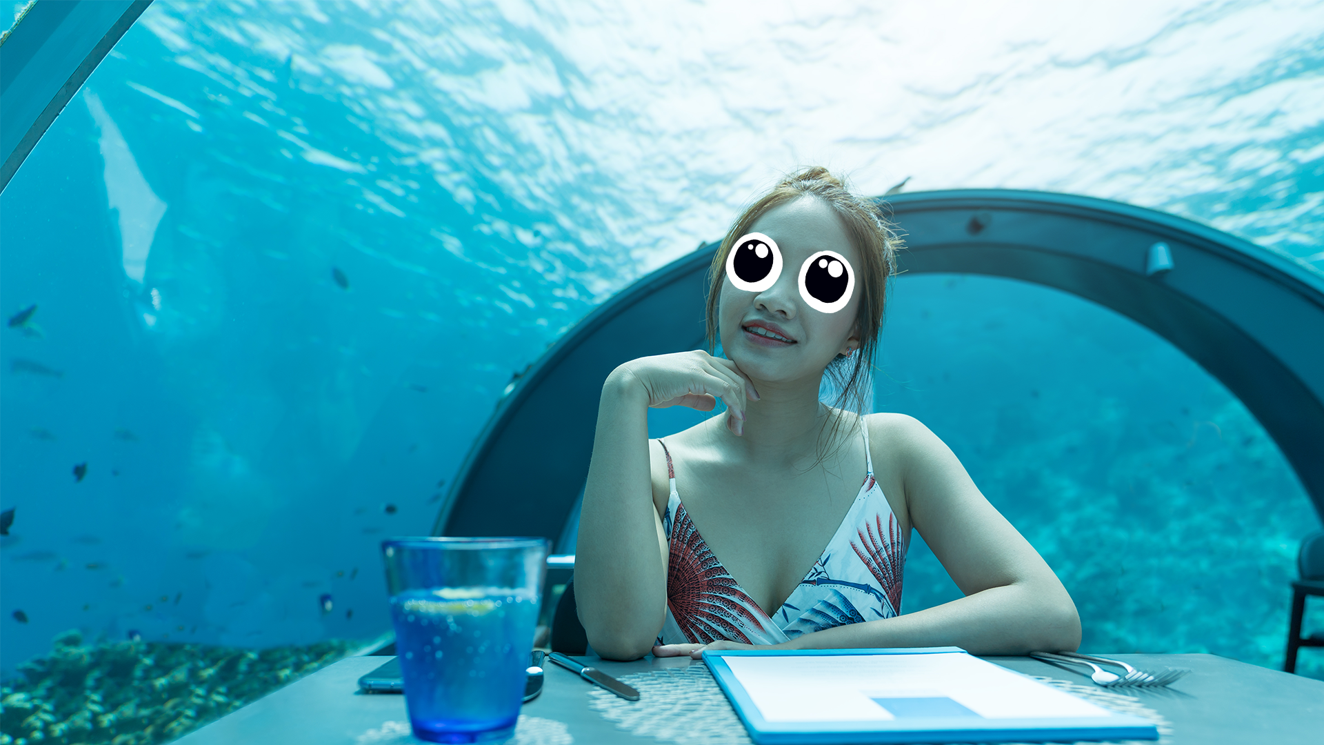 A woman sits in an underwater cafe