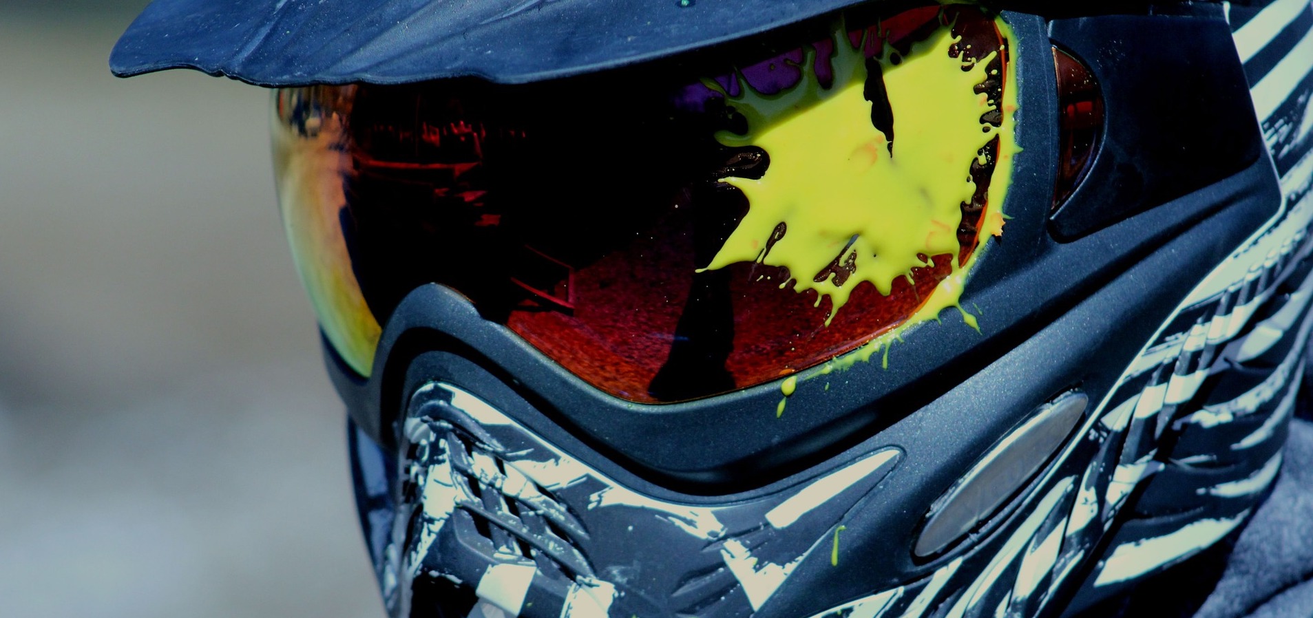 A close-up of a paintballer whose visor is covered in paint