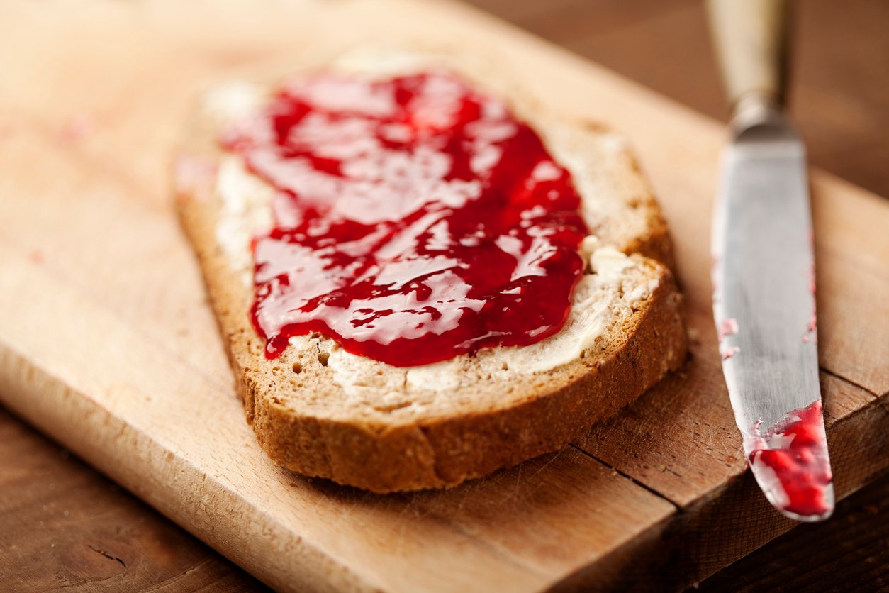 A hot slice of toast smeared with strawberry jam