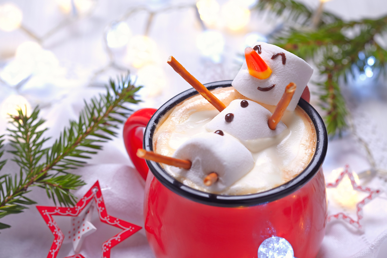 A marshmallow person relaxes in a mug of hot chocolate