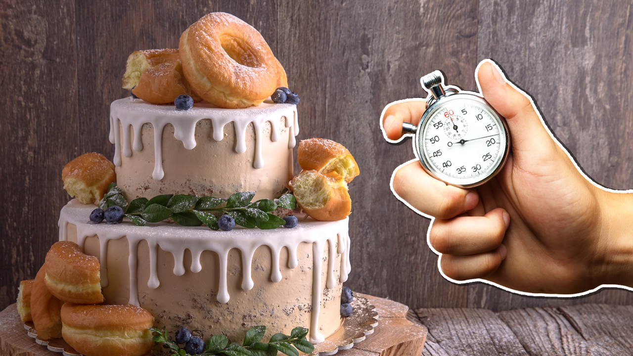 A stop watch being held in front of a big cake