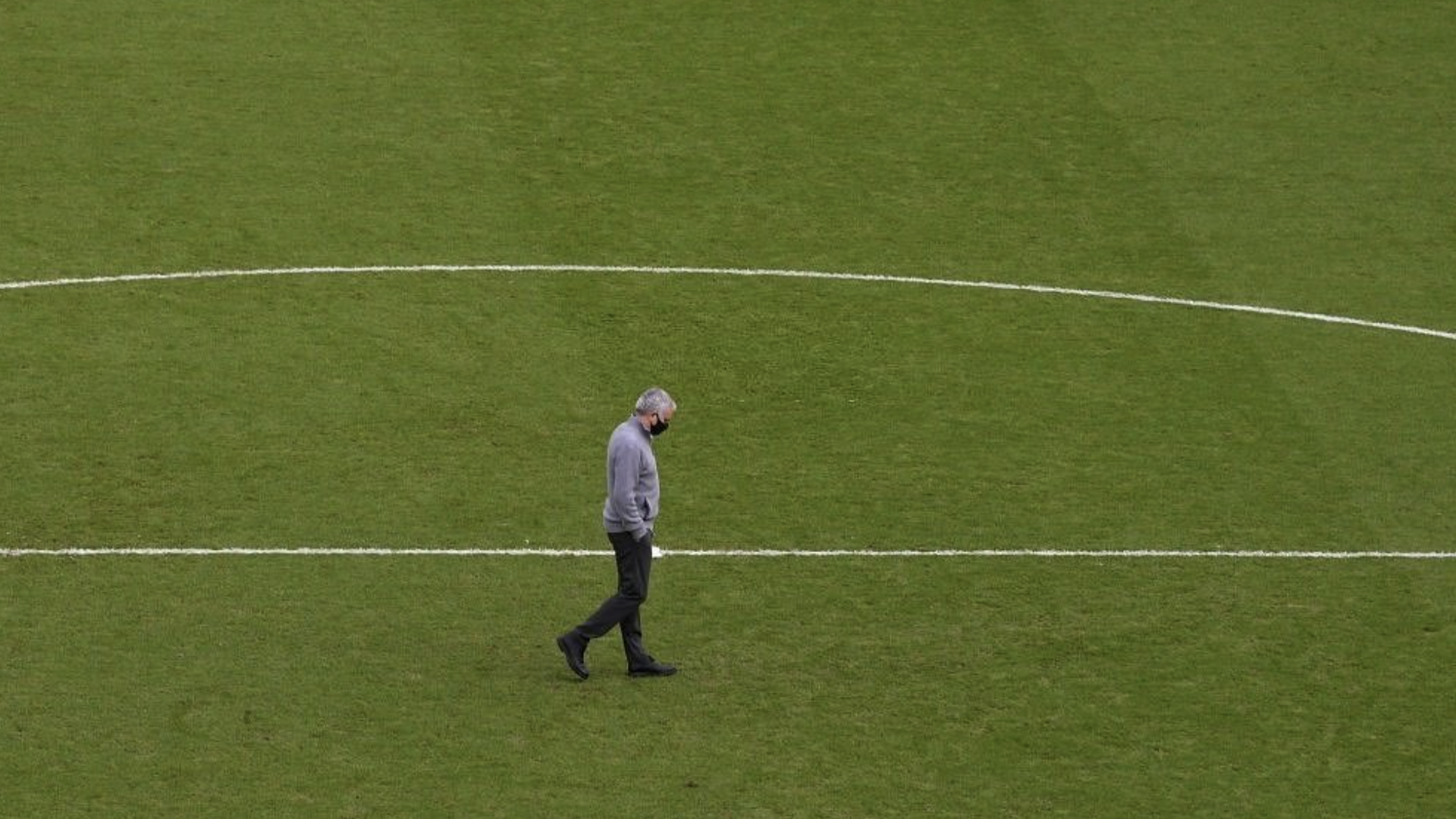 Jose Mourinho walks alone on an empty football pitch