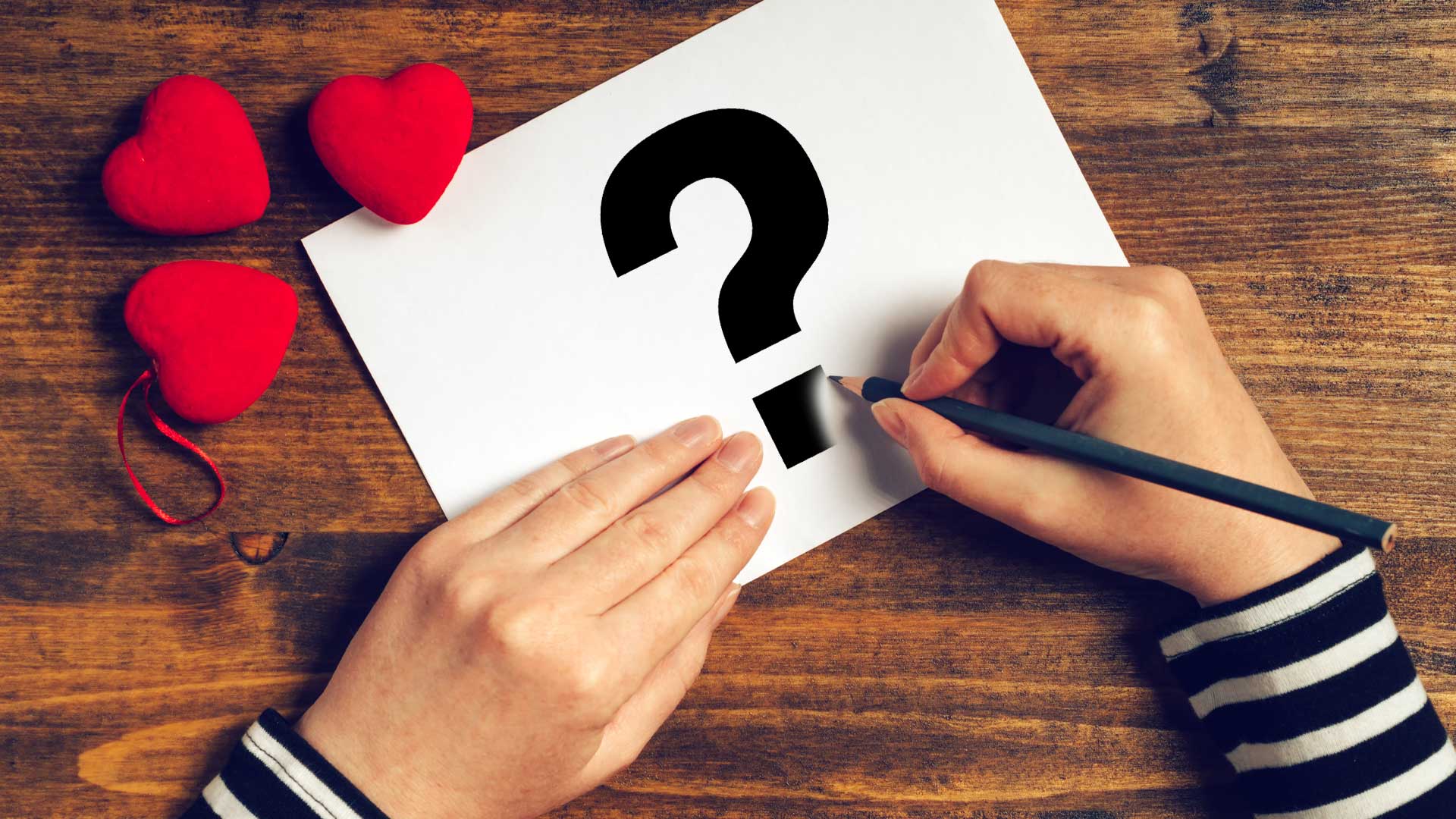 A person drawing a question mark on a Valentine's Day card