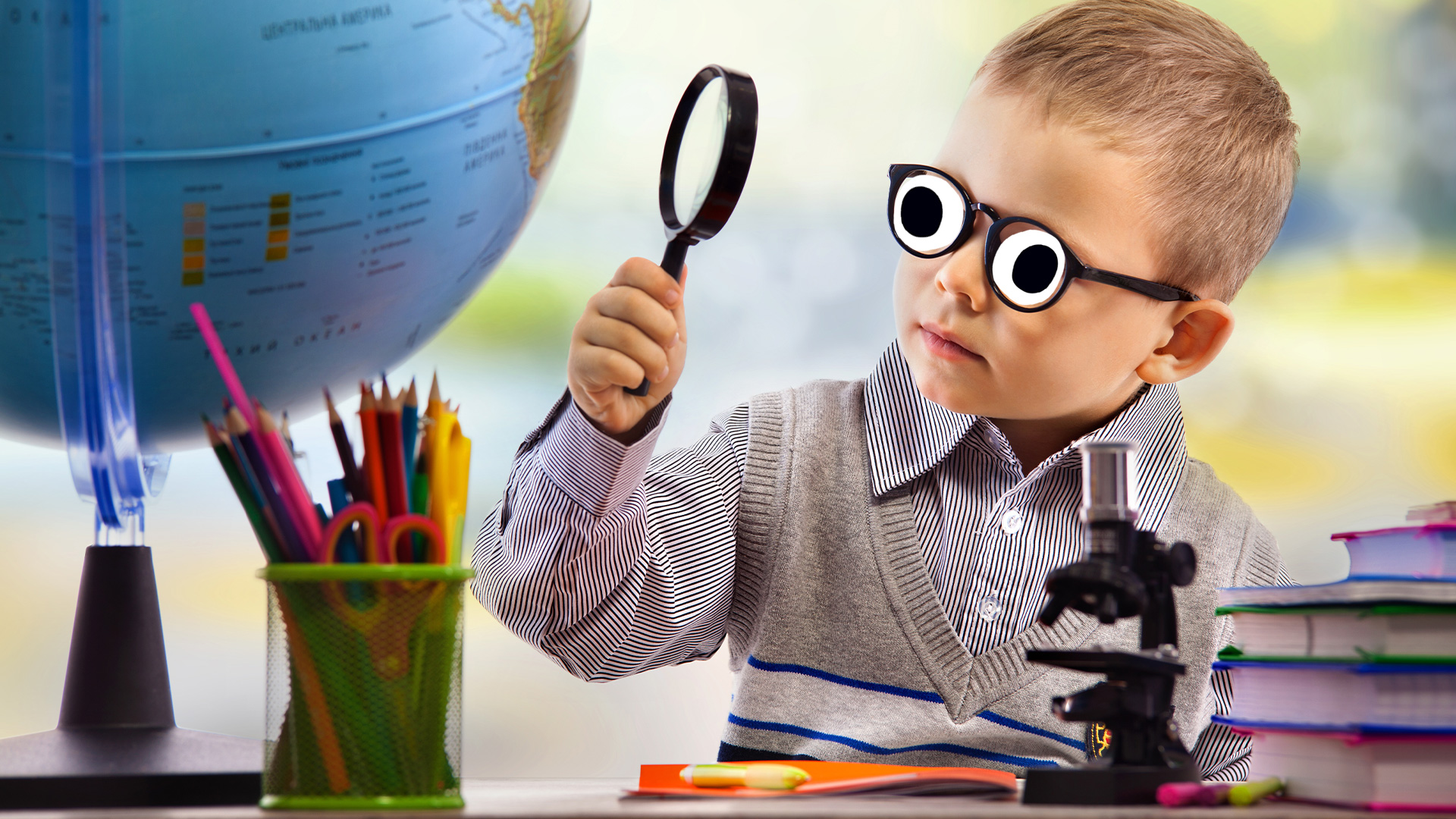 A boy looking at a globe with a magnifying glass