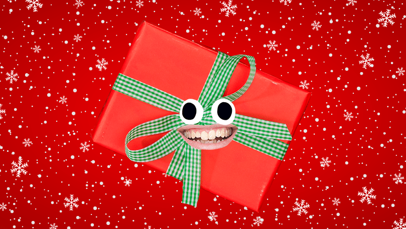 Smiling red Christmas present with a green ribbon wrapped around it