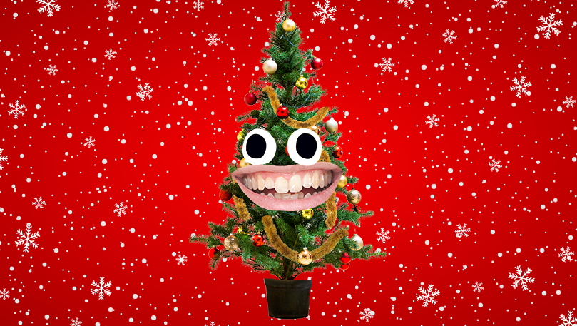 A laughing Christmas tree in front of a Christmas themed red background