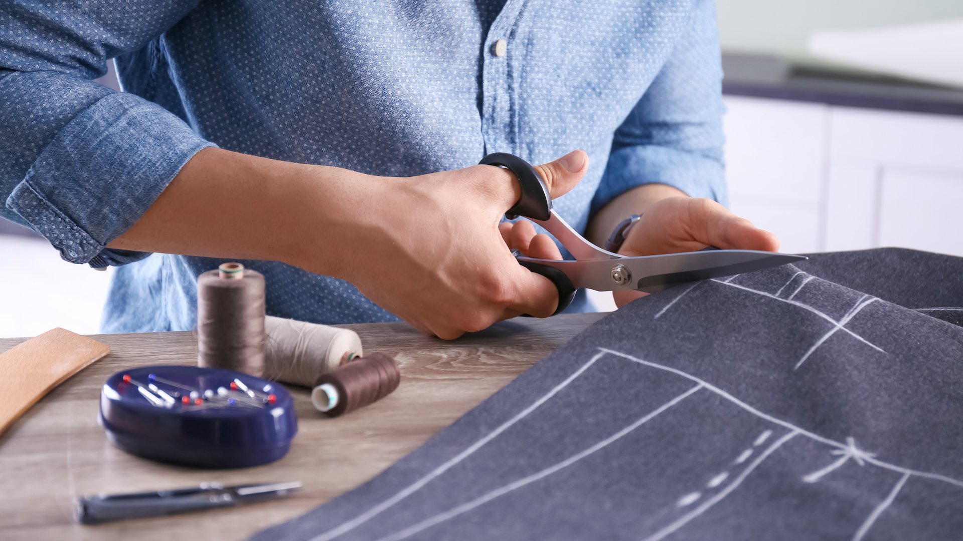 Tailor cutting fabric at table