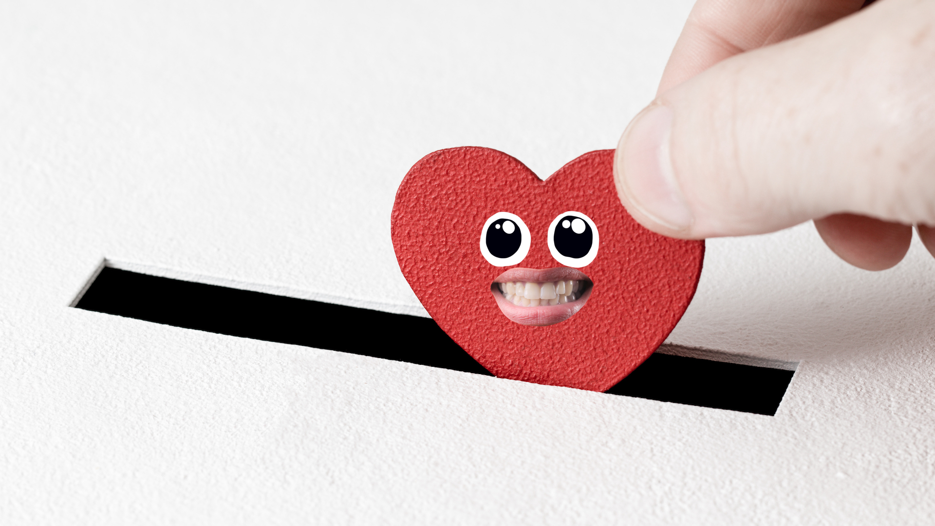 A heart shaped piece of card being dropped into a piggy bank slot
