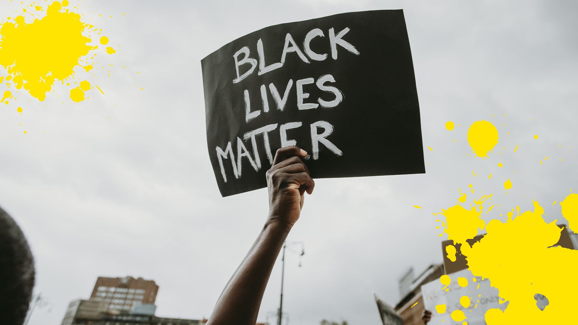 Hand holding a Black Lives Matter sign with yellow splats