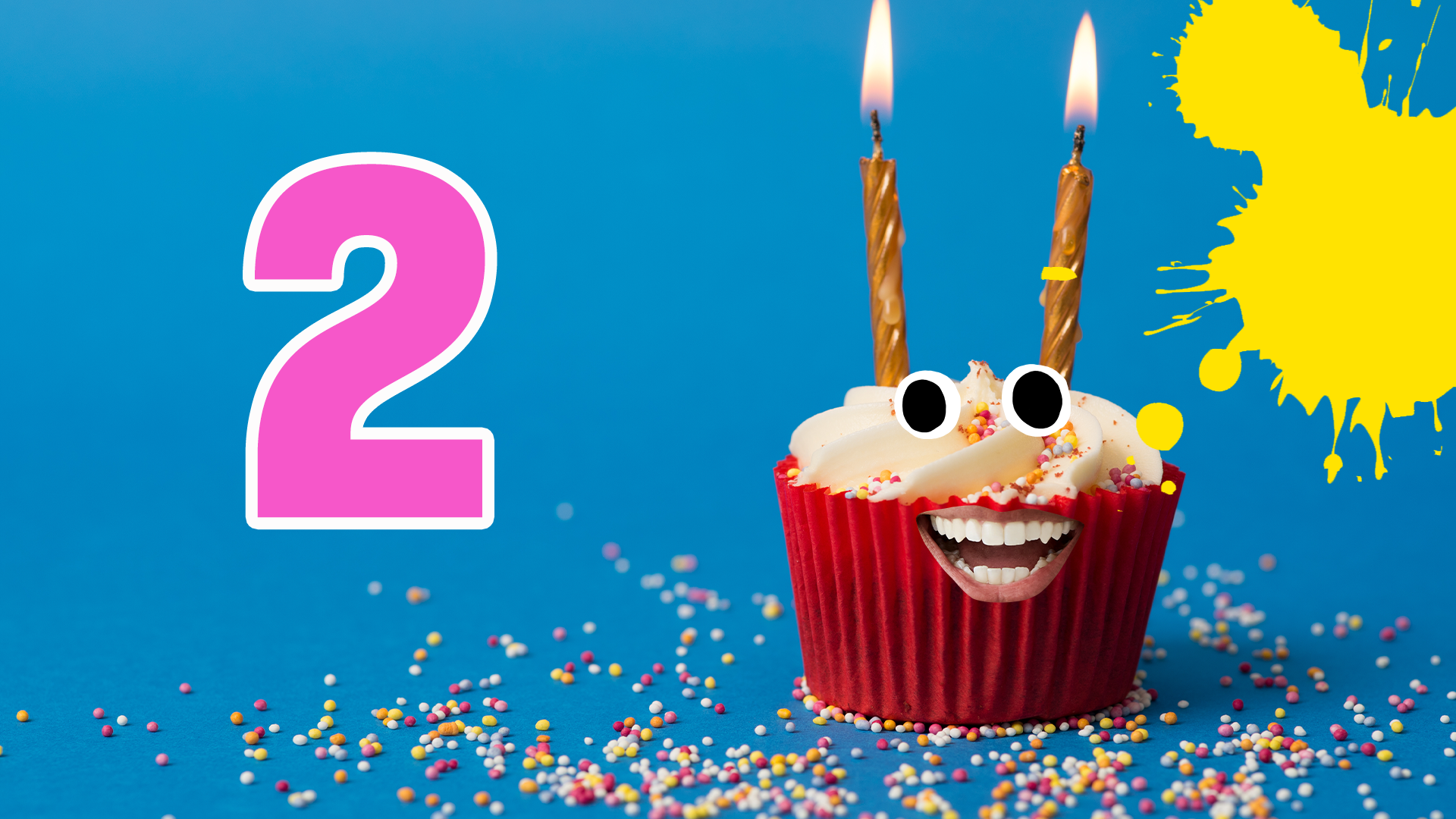 Cake with two candles and face, the number 2 and splats on blue background with sprinkles 