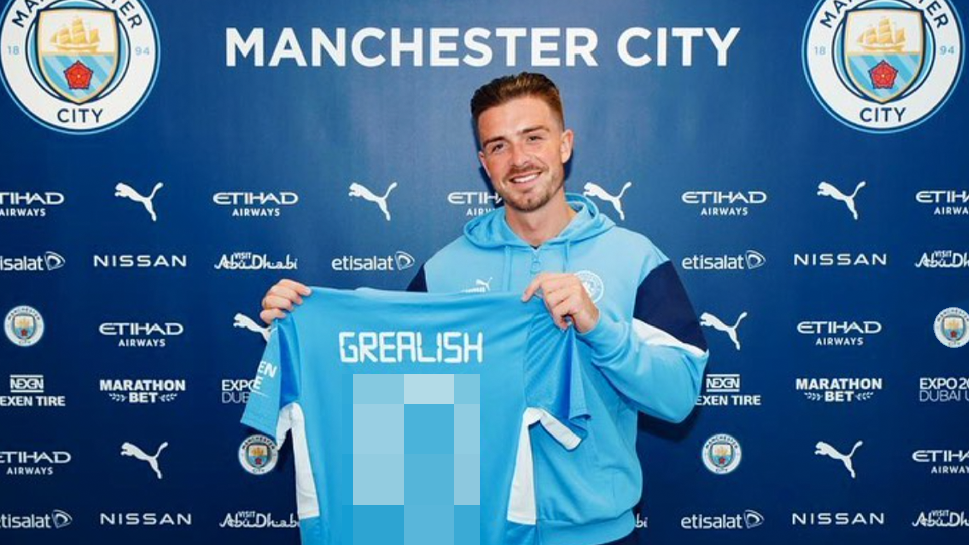 Jack Grealish holding up a Manchester City shirt