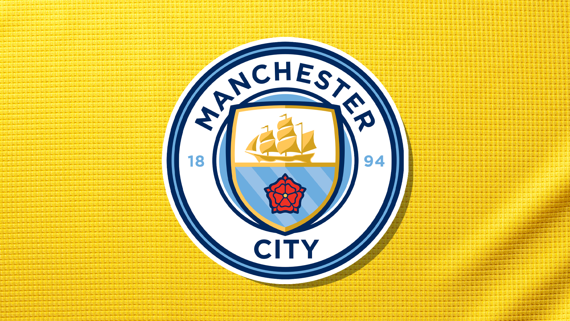 A Manchester City badge on a yellow shirt