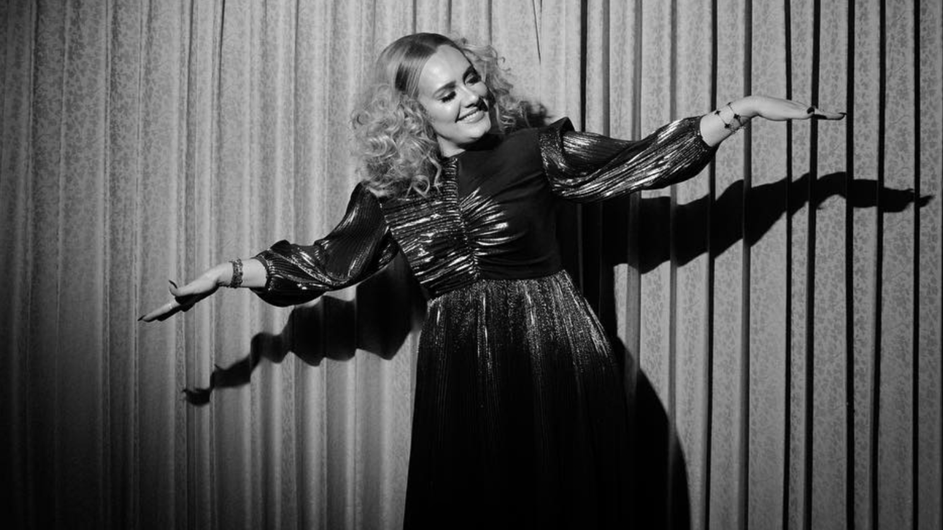 Adele in black and white in front of a stage curtain