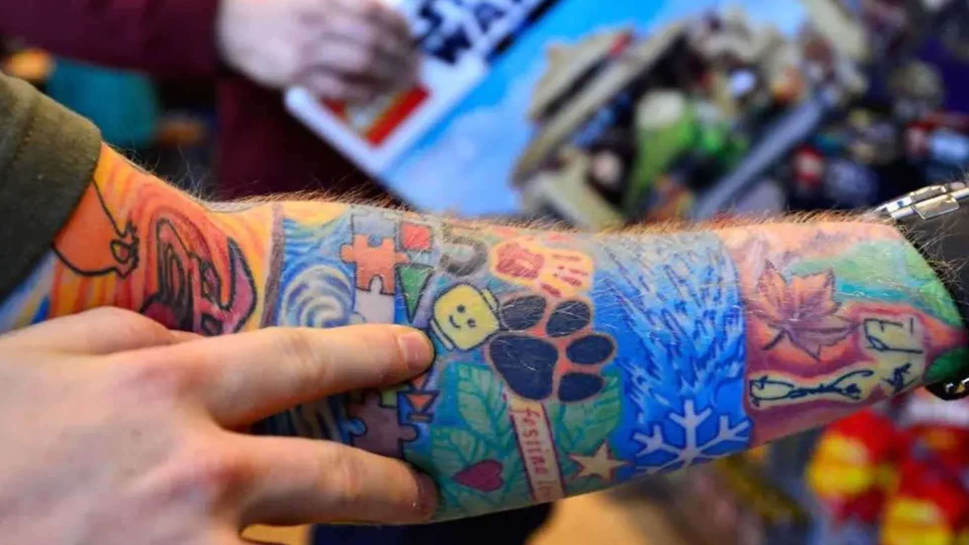 Ed Sheeran points to his many tattoos