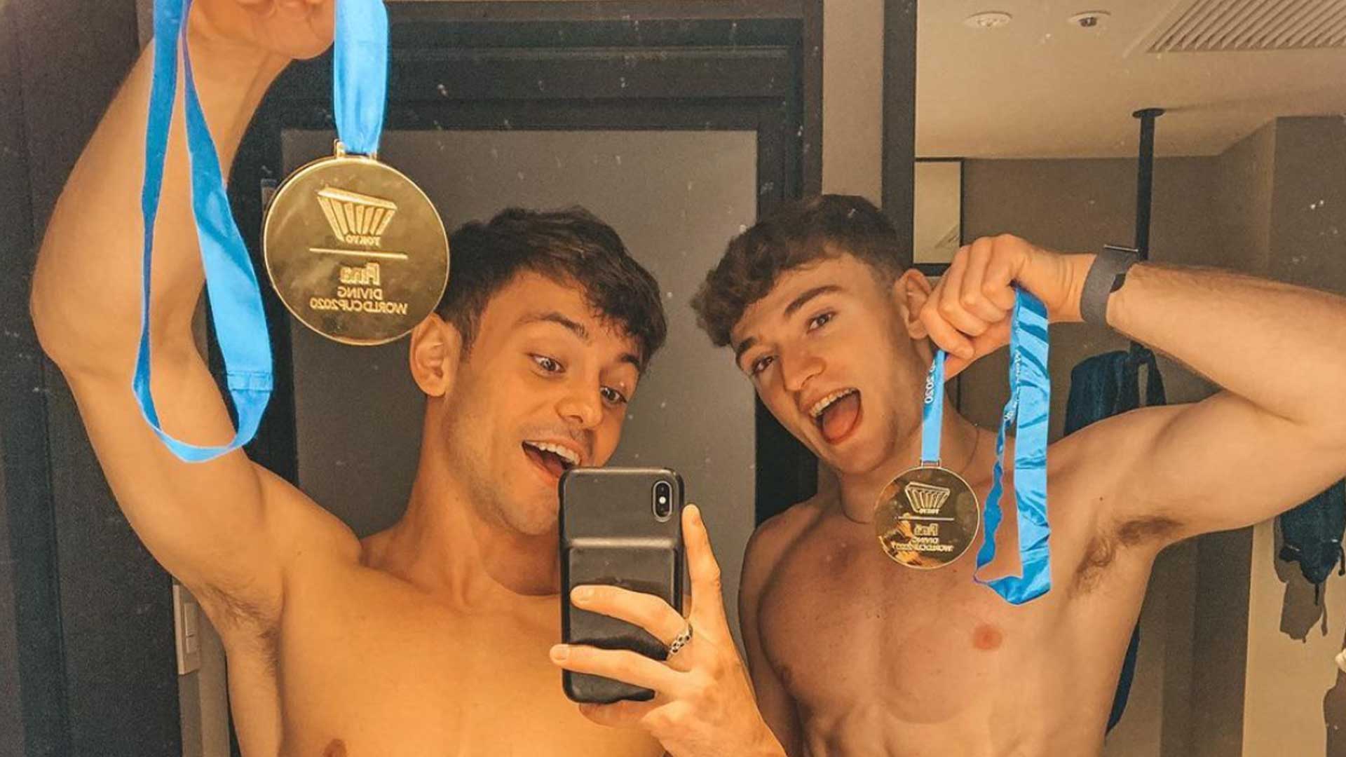 Tom Daley and Matty Lee posing with medals in a mirror