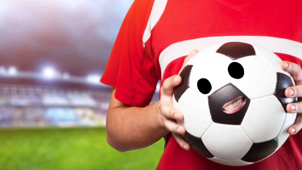 A footballer in a red shirt holds a ball