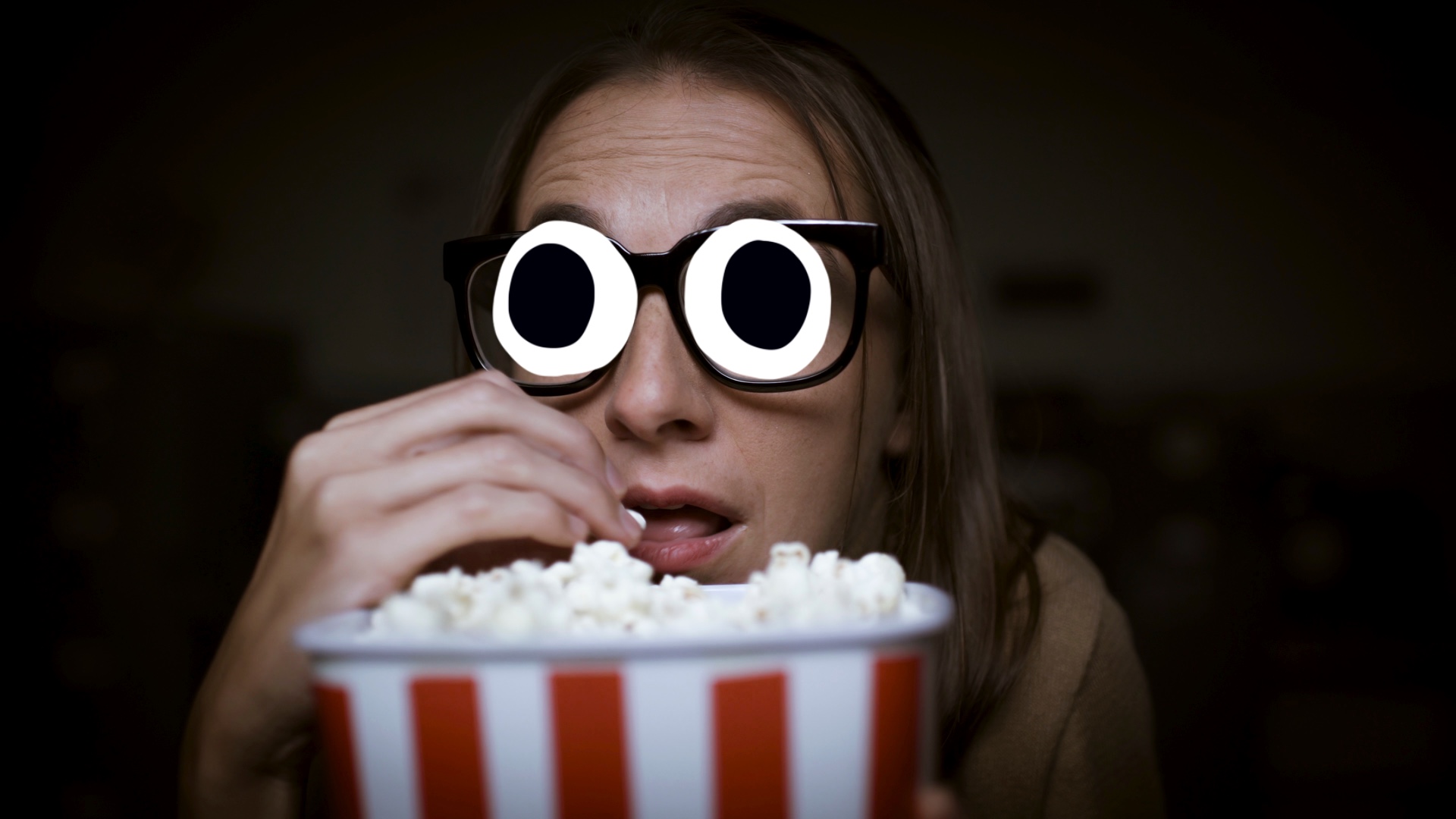 A person eating popcorn watching a movie
