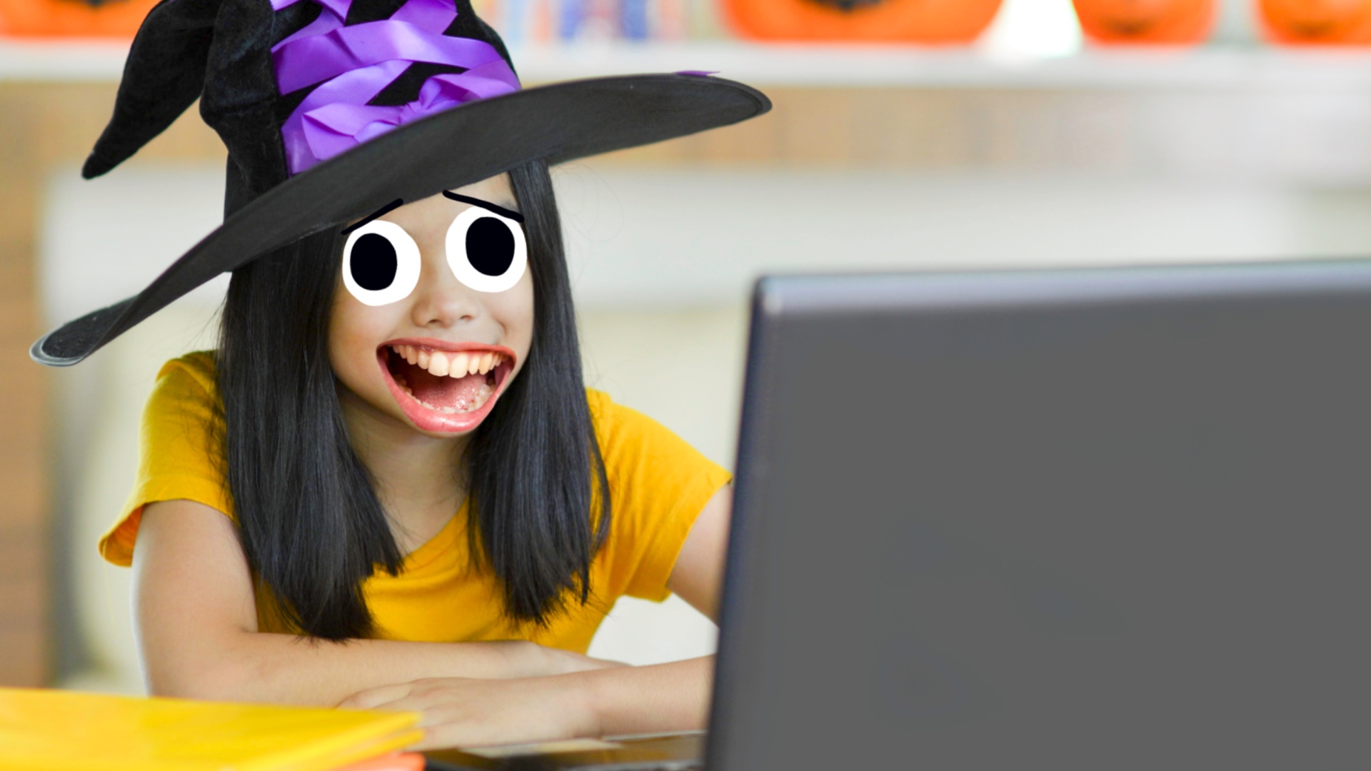 A student dressed as a witch, working on a laptop