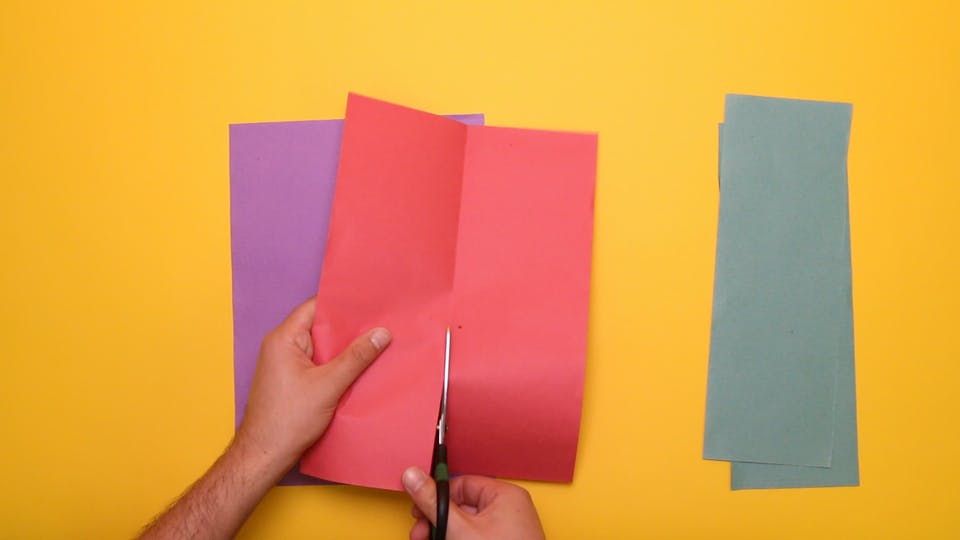 Fold each piece of paper in half, and cut down the middle, so that you get six long strips of coloured paper