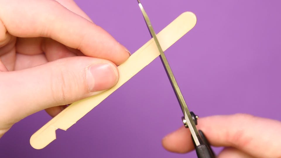Carefully cut 2 small notches in a lollipop stick with scissors, about 1 centimetre from the end