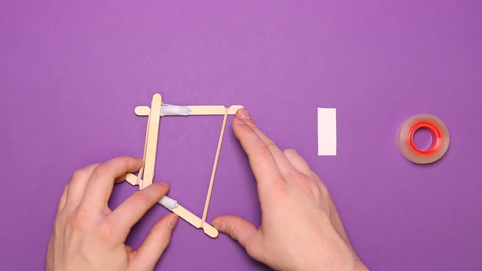 Stretch a second rubber band around the other end of the lollipop sticks