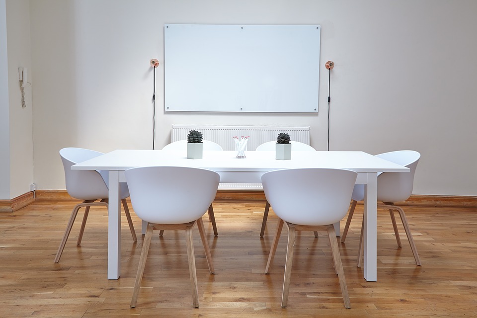 A whiteboard with a desk and chairs arranged in front
