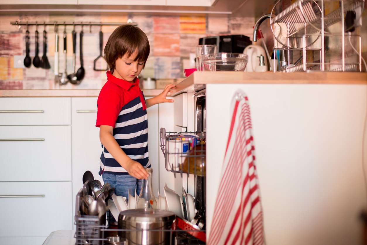 A boy stacking the dishwasher