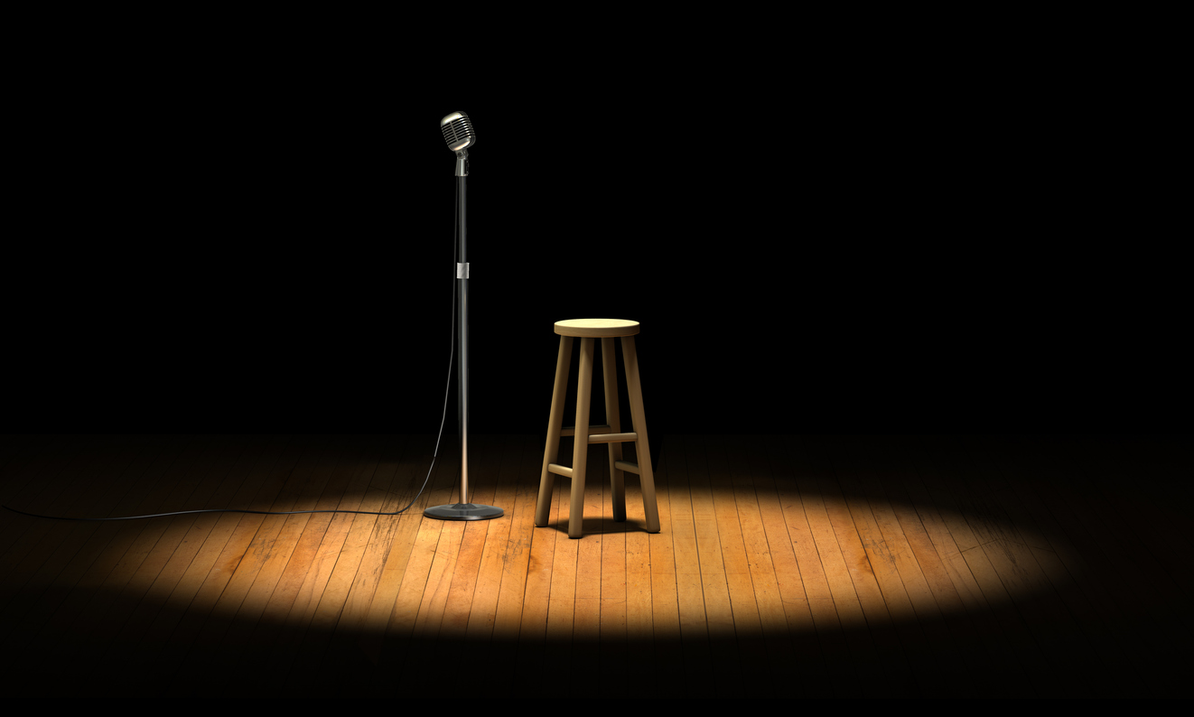 A microphone and stool on an empty stage