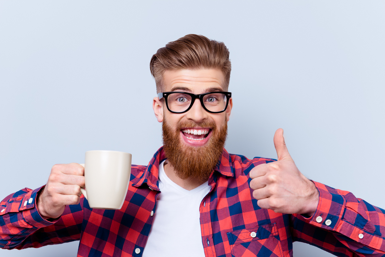 A bearded man looking thrilled with a cup of coffee