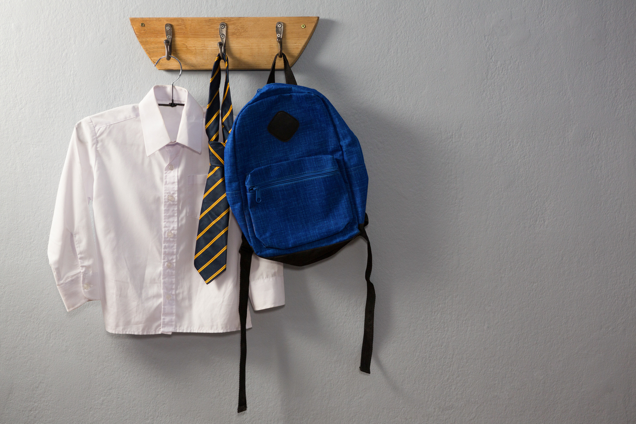 A school uniform and a bag hanging neatly on a hook