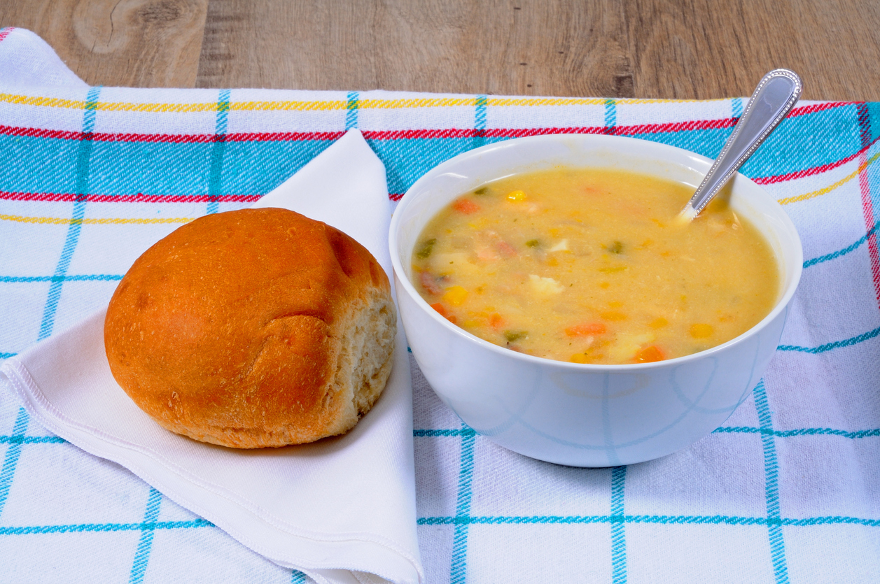 A bowl of soup and a bread roll