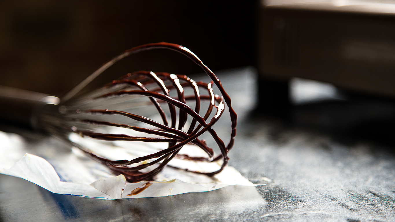 Messy whisk with gooey chocolate frosting