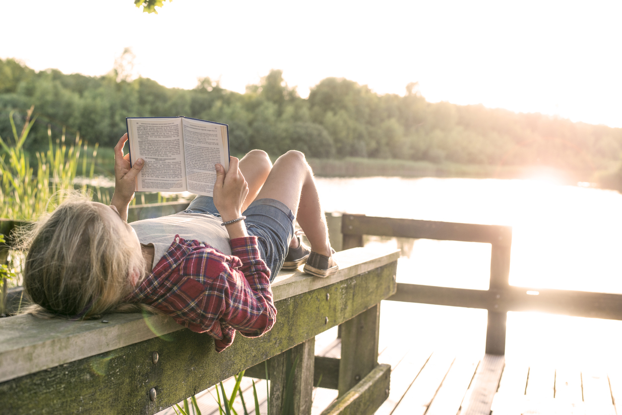 A child relaxing by the lake with a good book