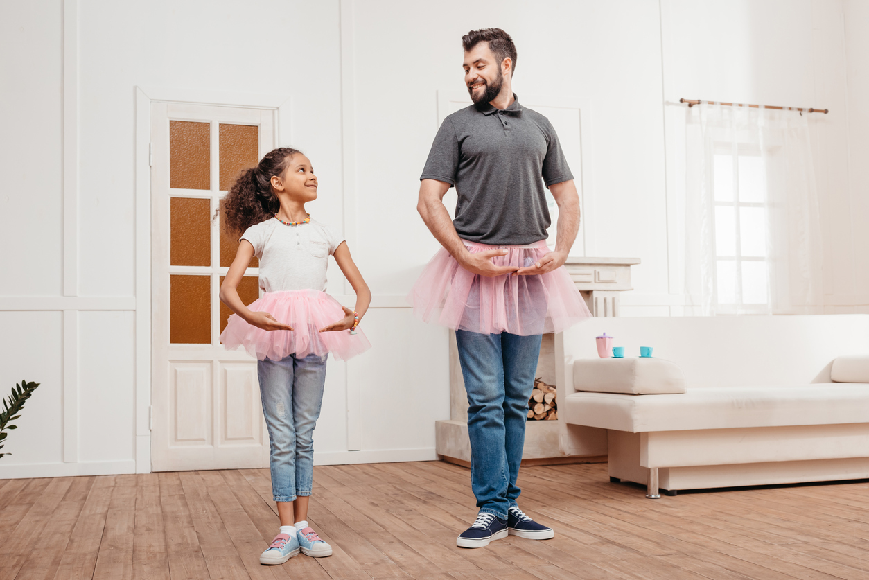 A family in pink tutu tulle skirts dance at home