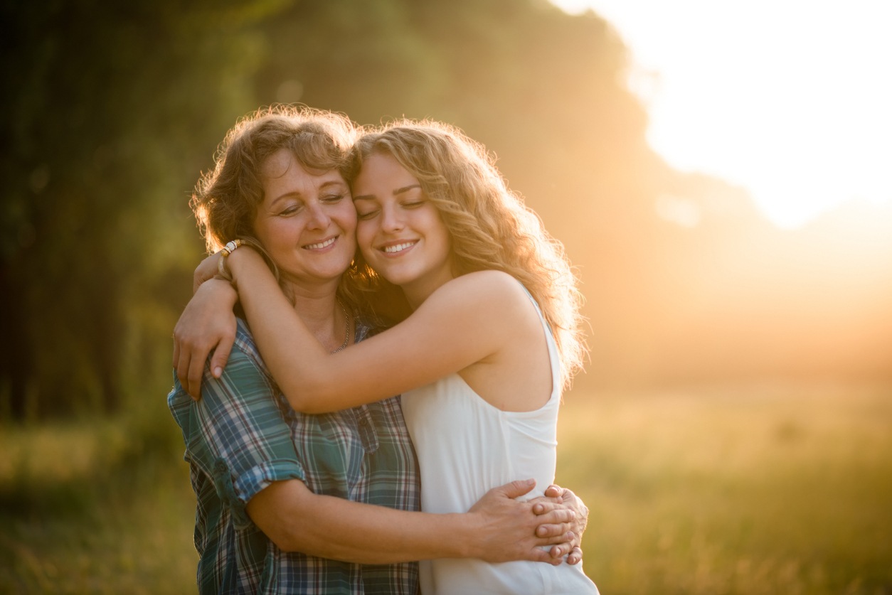 A mum and daughter hug in a field