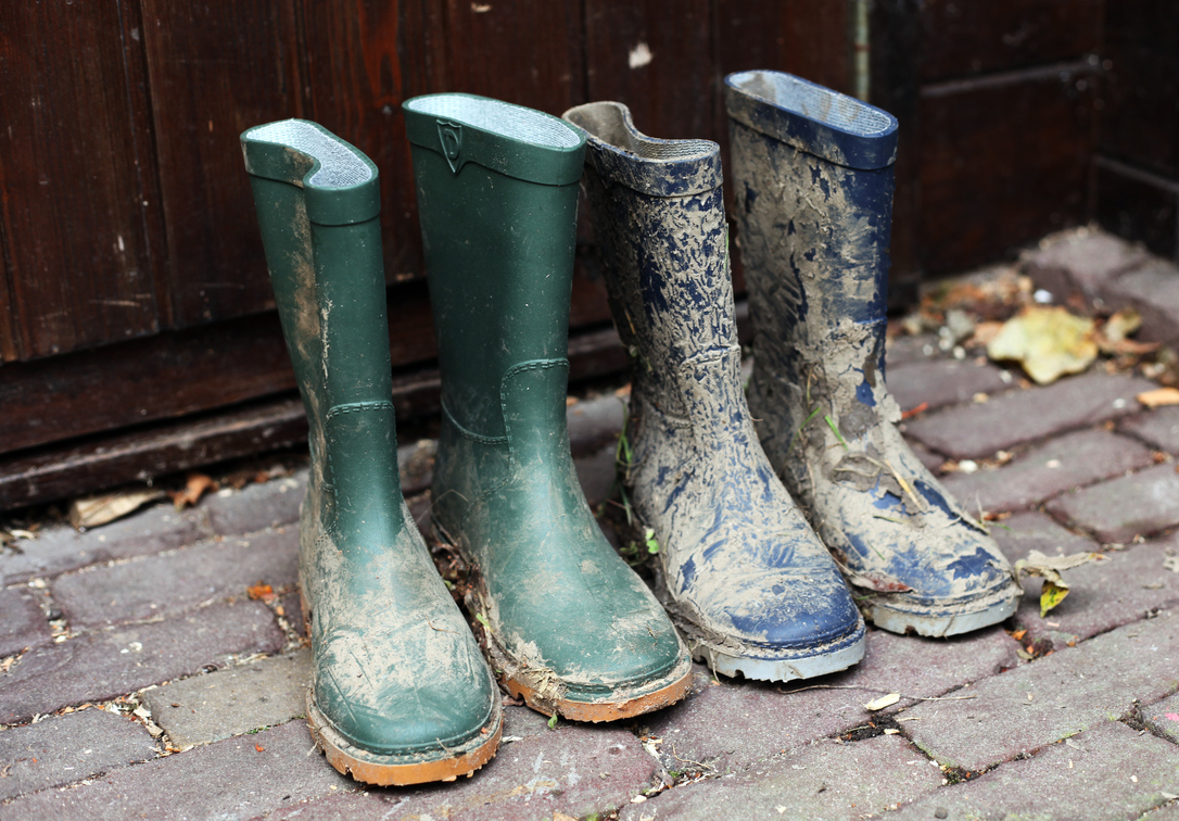 Two pairs of muddy boots outside a house
