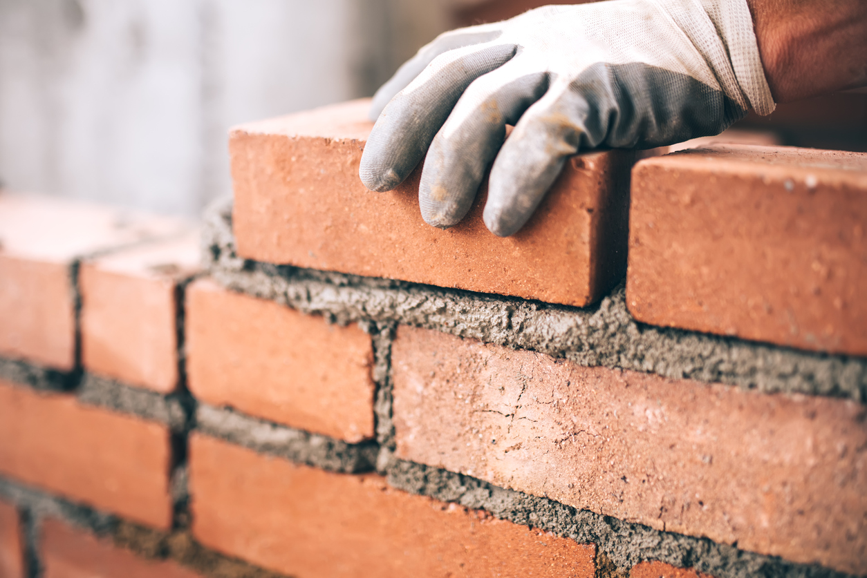 A person laying bricks with mortar