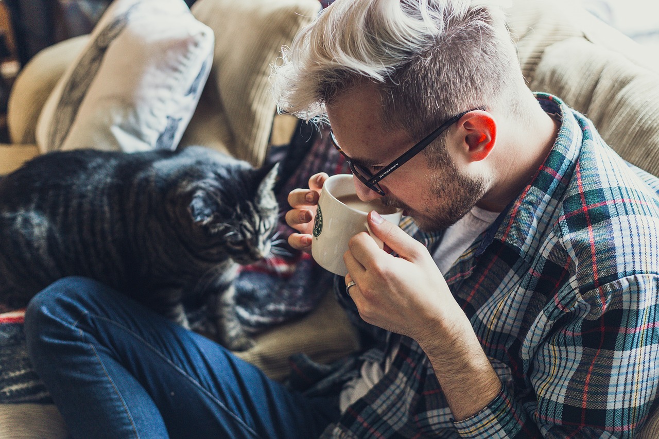 A man shielding his coffee from a thirsty pet