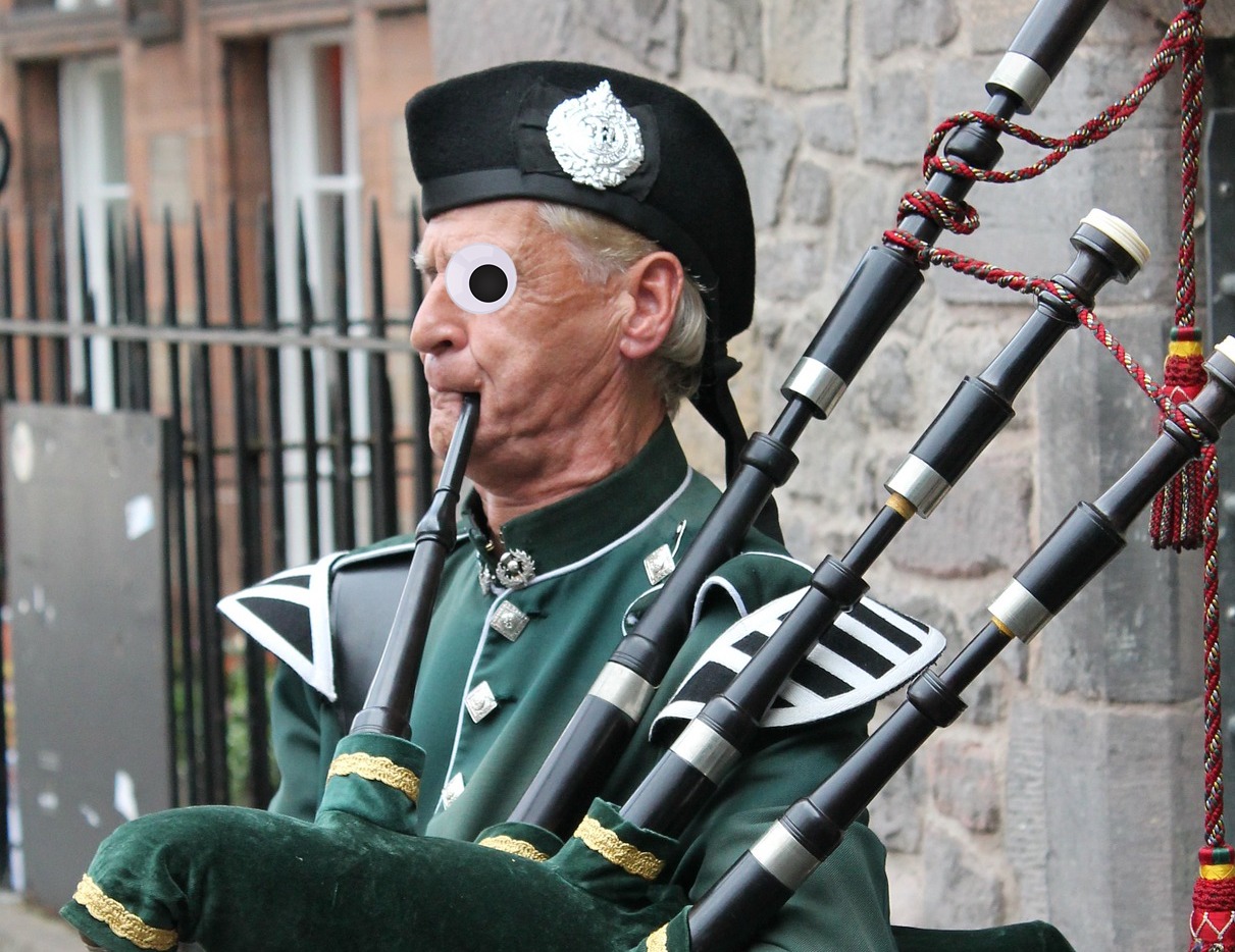 An elderly man blasting away on the bagpipes