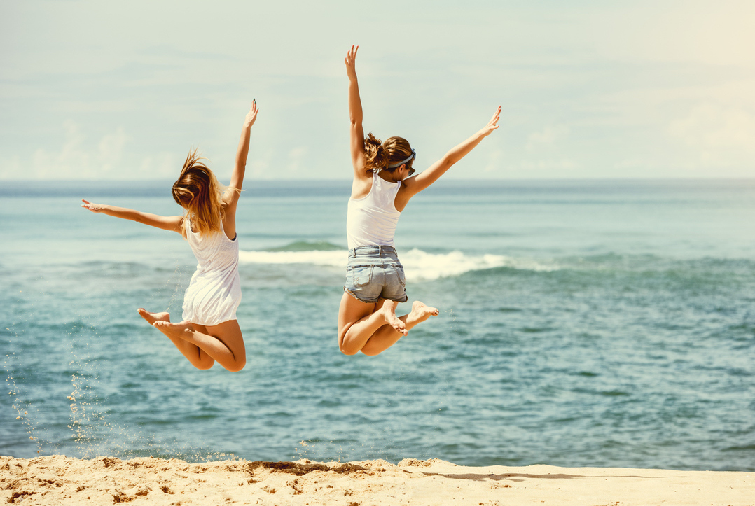 Two friends practice jumping on the beach