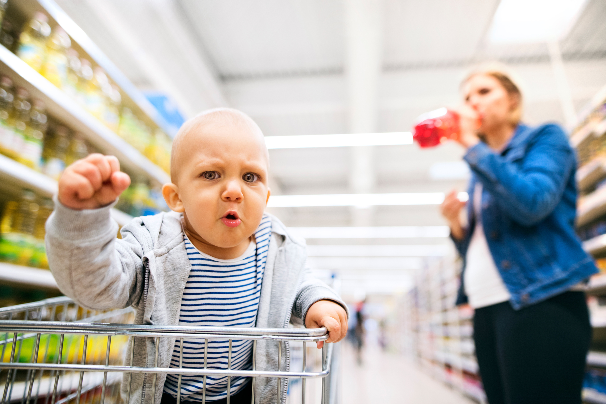 Angry looking baby sat in supermarket shopping trolly