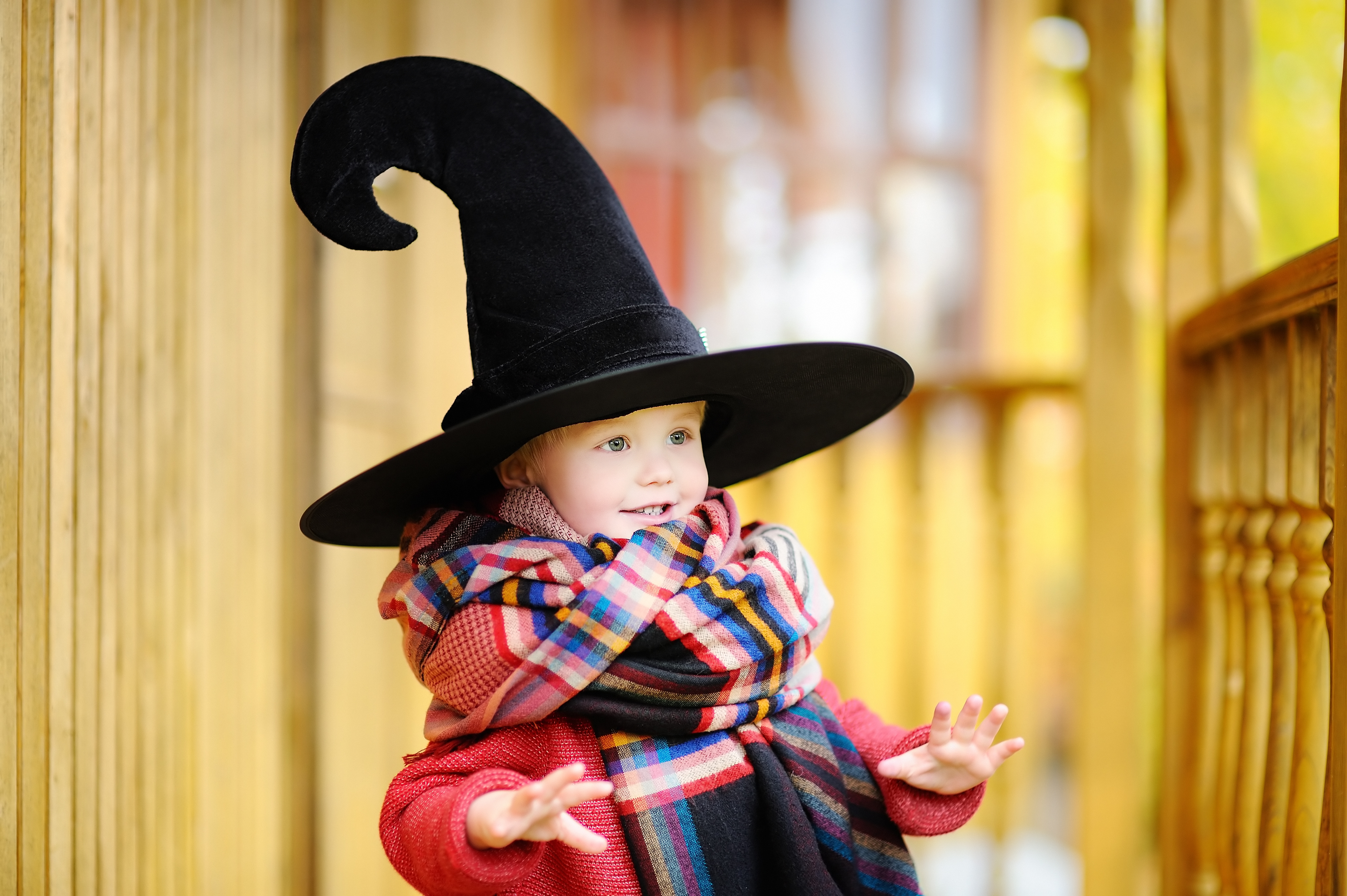 Young smiling girl wearing checkered scarf and witches hat