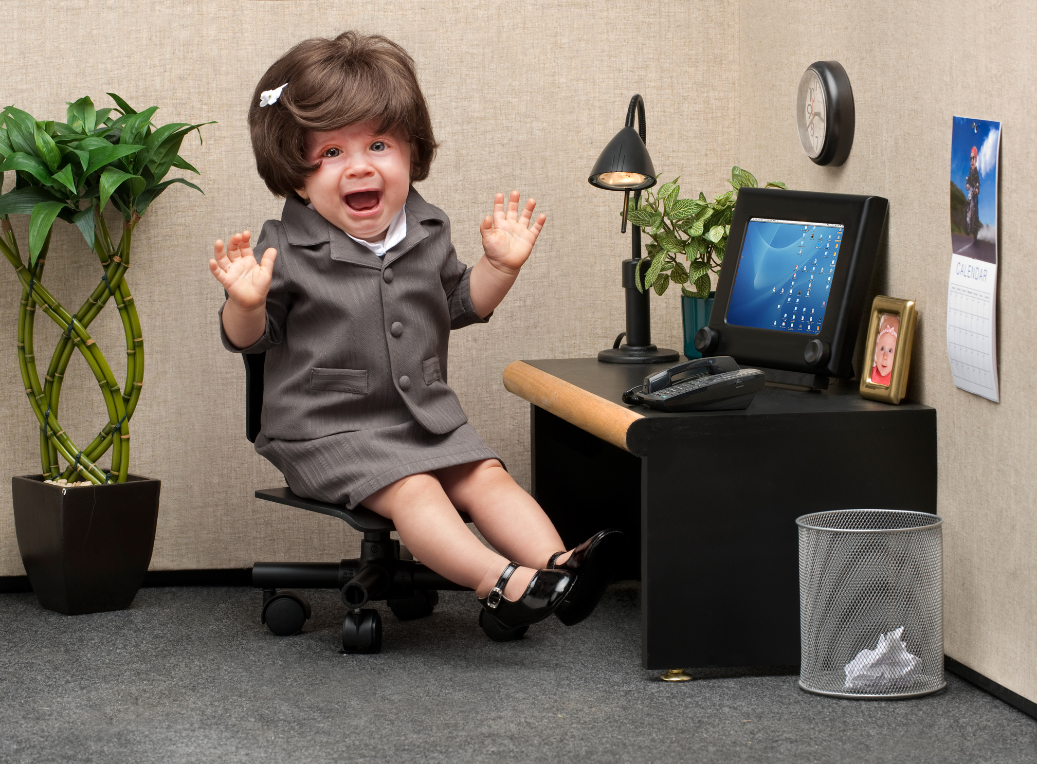Baby dressed as office worker sits crying at desk