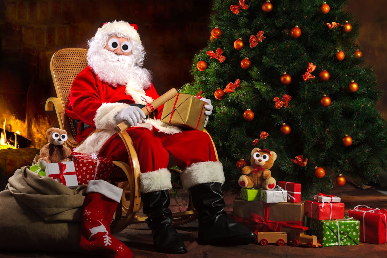 Santa Claus sitting on a rocking chair surrounded by presents