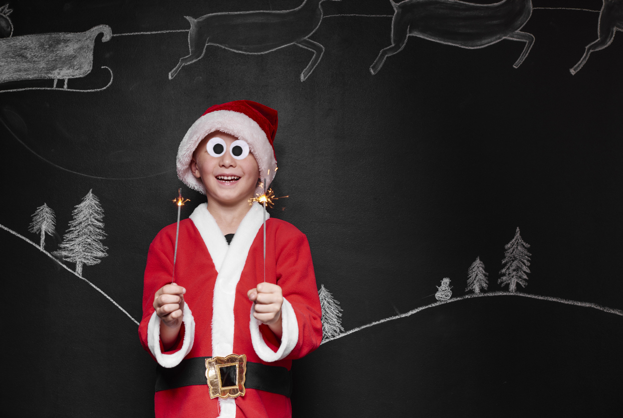 Child dressed up as santa claus enjoying a sparkler