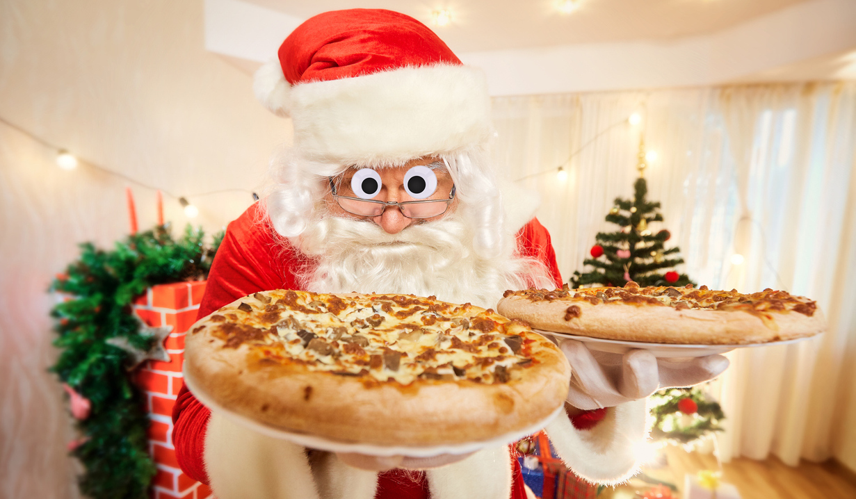 Santa holding two very large pizzas