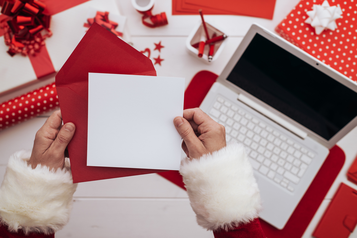 Christmas Quiz: Hands holding a blank card and a red envelope