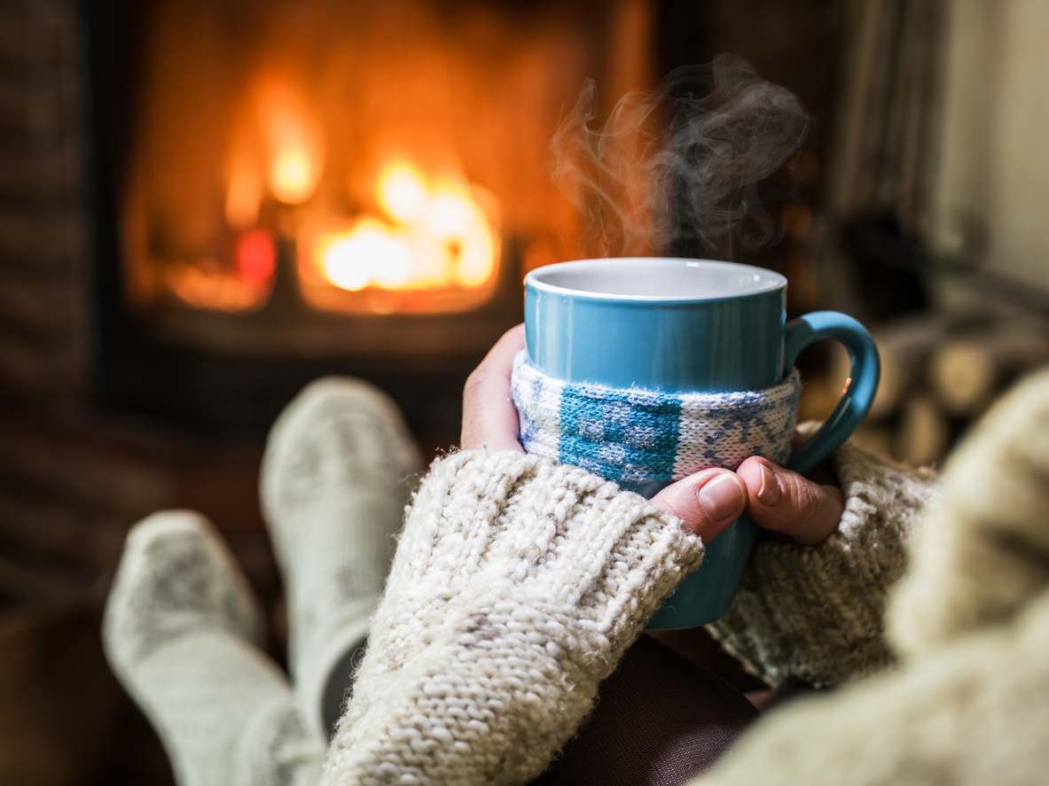 Someone relaxing with a hot drink in front of a roaring fire