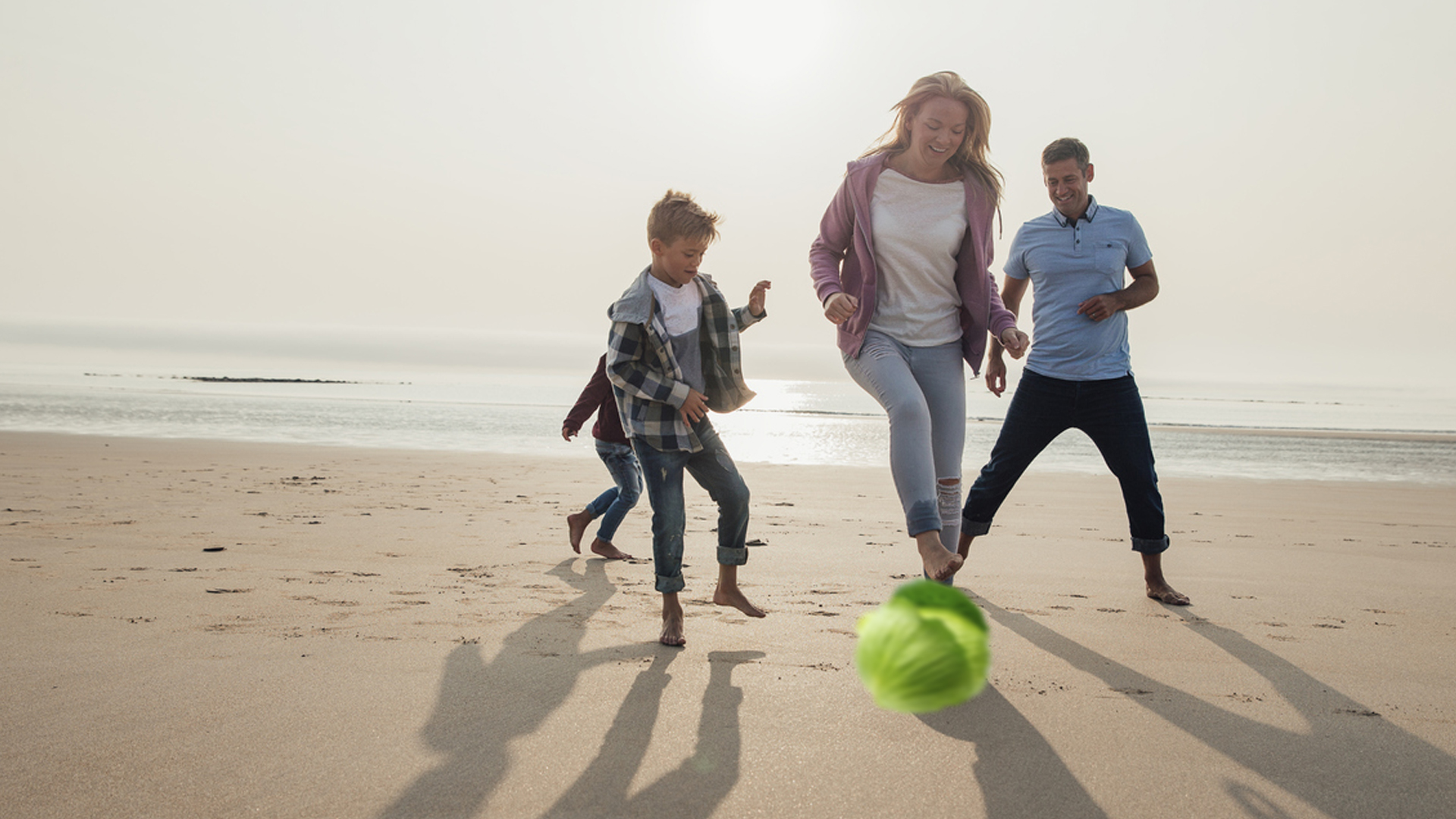 A family kicking a cabbage around on the beach