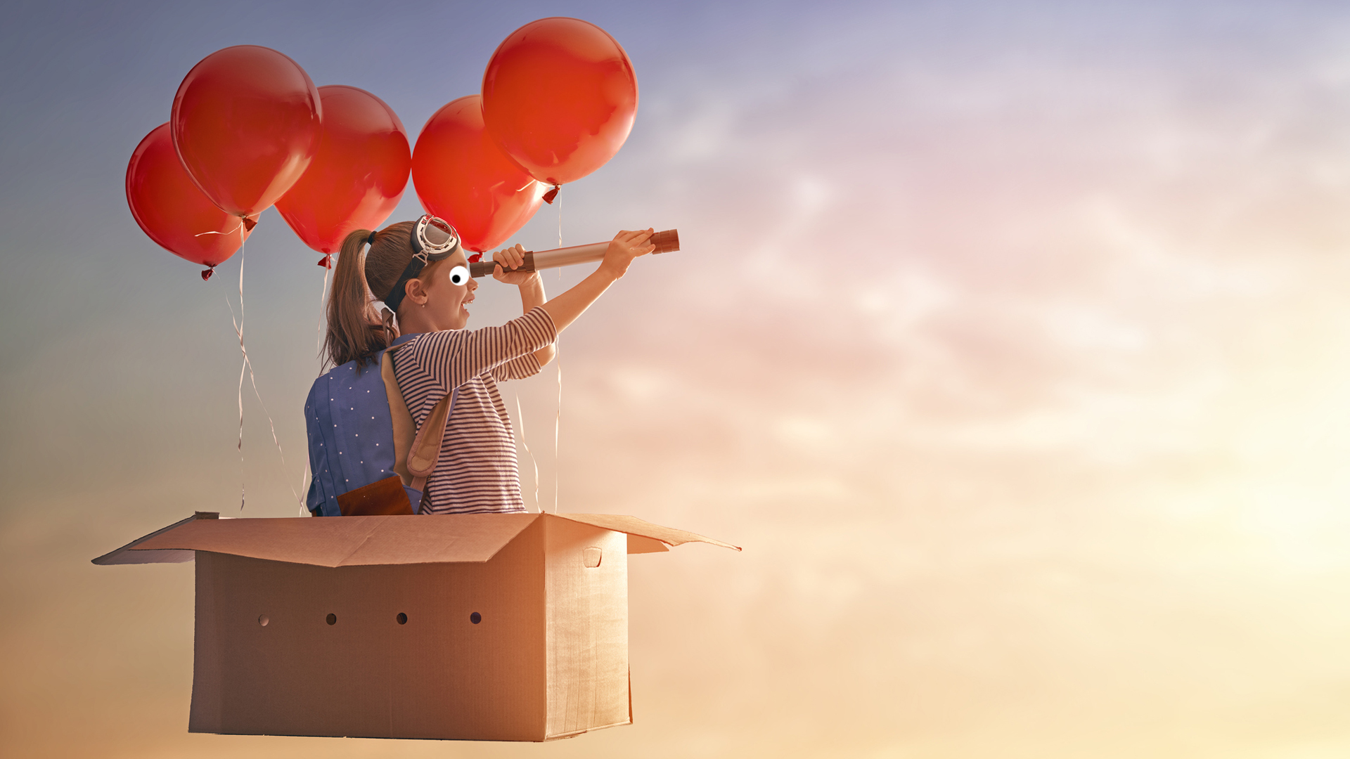 A girl flying around in a box suspended by red balloons
